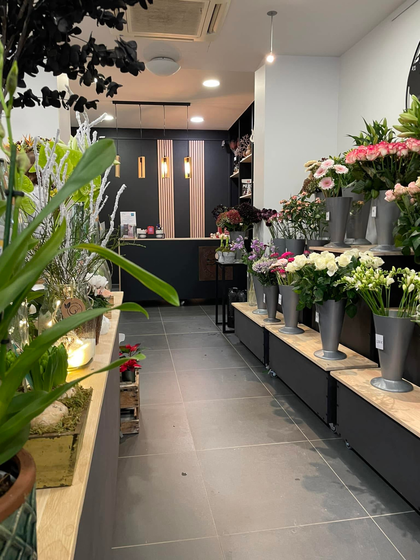 Magasin Art Floral Desablens : présentoirs en bois, vases gris et fleurs coupées de saison.